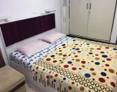 تخت خواب با روتختی رنگی و کمد دیواری اتاق خواب آپارتمان در شیراز