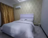 تخت خواب با روتختی سفید و پرده قهوه ای رنگ اتاق خواب آپارتمان در عفیف آباد