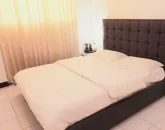 تخت خواب با روتختی سفید و پرده های کرمی رنگ اتاق خواب واحد آپارتمان در عفیف آباد