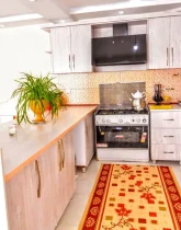 آشپزخانه با کابینت های چوبی، یخچال، هود و گل های خانه ویلایی در قصر دشت 4588654